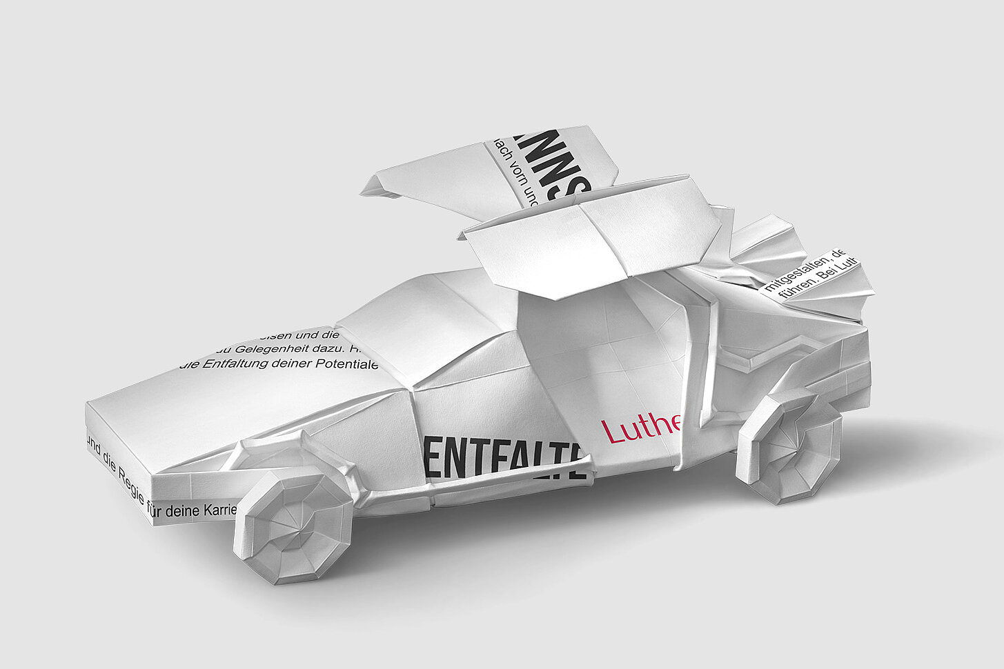 Ein Auto aus Papier, gefaltet mit verschiedenen Texten, steht im Vordergrund. Es symbolisiert Kreativität und Möglichkeiten im Zusammenhang mit Karriere und persönlicher Entfaltung. Der Schriftzug „Luther“ ist deutlich sichtbar, was auf eine Verbindung zu einem Unternehmen oder Projekt hinweist.